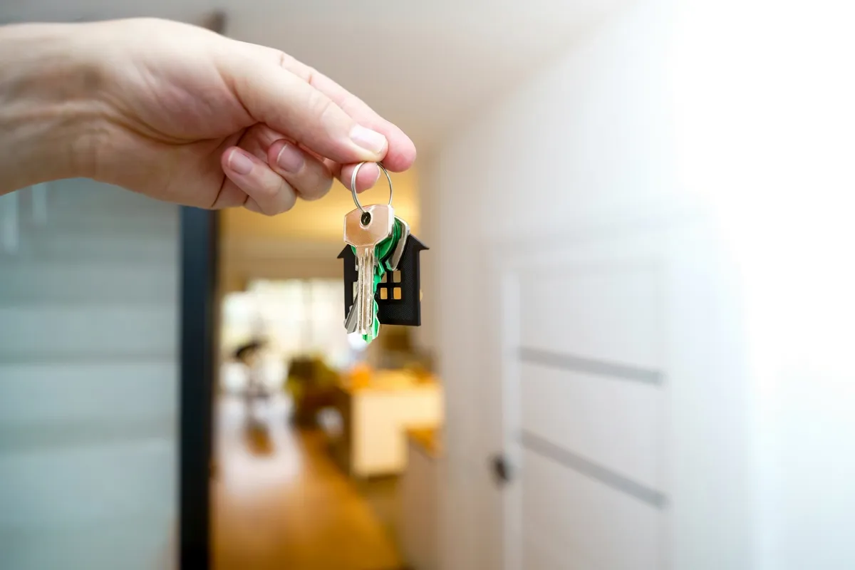 Mão segurando chave de casa na entrada