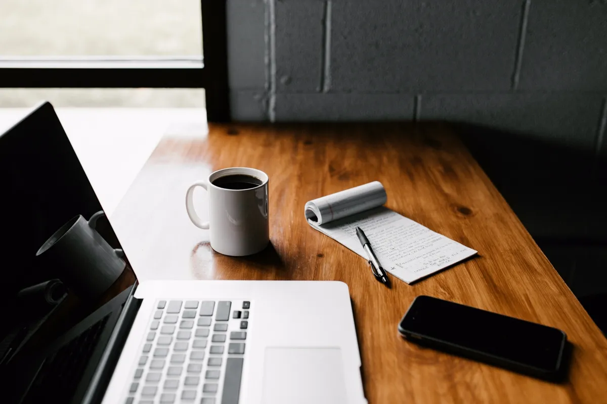 Notebook e celular sobre uma mesa de trabalho